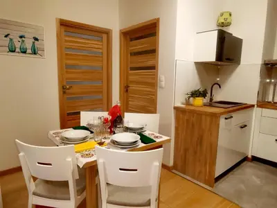 a kitchen with a table with white chairs and a small kitchen at apart Wilga in Kraków