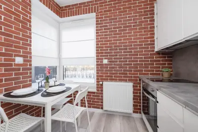 a kitchen with a white table and a brick wall at Dąbska Studio with Terrace & Parking by Noclegi Renters in Kraków