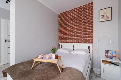 a bedroom with a brick wall and a bed with a table at Dąbska Studio with Terrace & Parking by Noclegi Renters in Kraków