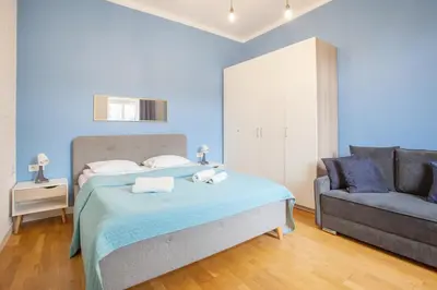 a blue bedroom with a bed and a couch at Smart Old Town Apartment in Kraków