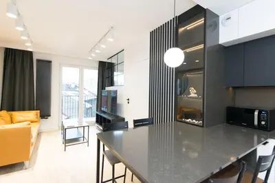 a kitchen with a black counter top and a living room at Ghetto Heroes Square Lwowska 10 A/C p4you pl in Kraków