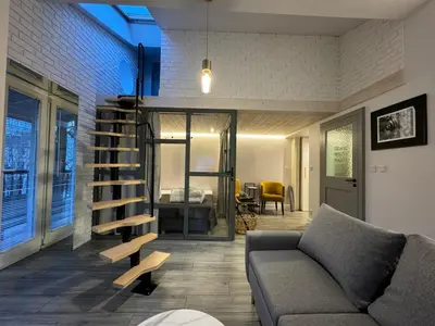 a living room with a couch and a spiral staircase at Balcony Bliss Main Square Loft in Kraków