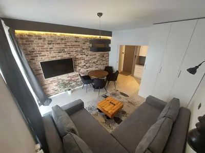a living room with a couch and a brick wall at Apartament nad Wisłą, bezpłatny parking, AWG APARTMENTS in Kraków