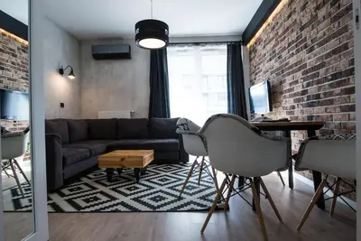 a living room with a couch and a brick wall at Apartament nad Wisłą, bezpłatny parking, AWG APARTMENTS in Kraków