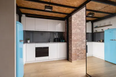 a kitchen with white cabinets and a brick wall at Deluxe Loft Apartment Lubelska with Mezzanine by Noclegi Renters in Kraków