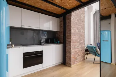 a kitchen with white cabinets and a brick wall at Deluxe Loft Apartment Lubelska with Mezzanine by Noclegi Renters in Kraków