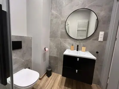 a bathroom with a white toilet and a mirror at New comfortable apartment with patio on Klimeckiego street in Kraków