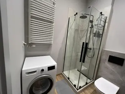 a bathroom with a washing machine and a shower at New comfortable apartment with patio on Klimeckiego street in Kraków