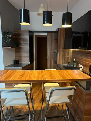 a kitchen with a wooden counter with stools at City Center Apartment in Kraków