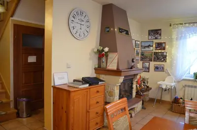 a living room with a fireplace and a clock on the wall at Gospodarstwo Agroturystyczne Stajnia Grudki Energylandia Zator in Zator