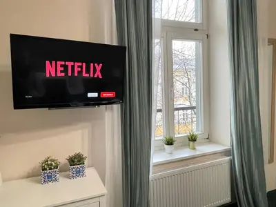 a television on a wall in a room with a window at Gertrudy 10 Residence - 1-Minute Walk to the Old Town in Kraków