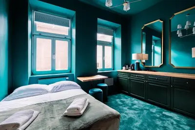 a bedroom with blue walls and a bed with a mirror at Green Gertrudy in Kraków