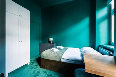 a bedroom with green walls and a bed with a table at Green Gertrudy in Kraków