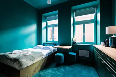 a blue bedroom with a bed and two windows at Green Gertrudy in Kraków
