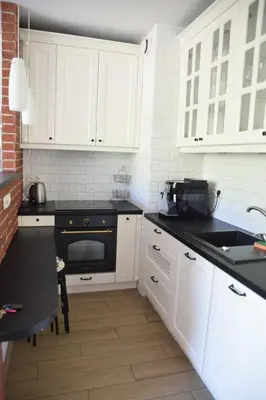 a kitchen with white cabinets and a black oven at Apartament z podziemnym parkingiem ulica Wroclawska in Kraków