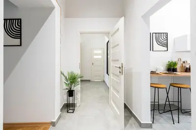 a hallway with white walls and a kitchen with stools at Cracow Best Location Apartment No:6 by Cozyplace in Kraków