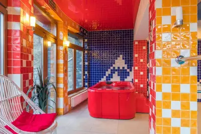 a bathroom with a red bucket in a room with tiles at Hotel Karolek in Zawoja