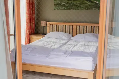 a bed with a wooden frame and white sheets at Hotel Karolek in Zawoja