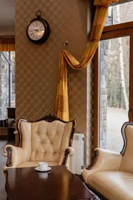 a living room with a couch and a table and a clock at Hotel Karolek in Zawoja