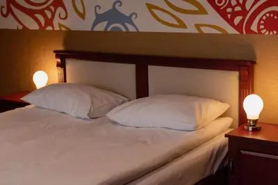 a bed with two pillows and two lights on it at Hotel Karolek in Zawoja
