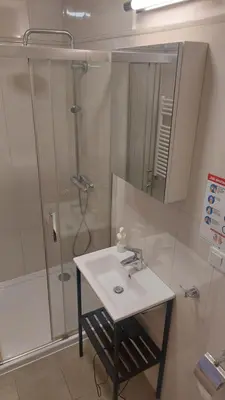 a bathroom with a sink and a shower with a mirror at Kazimierz Center Apartments Halicka 5 in Kraków