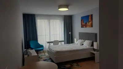 a bedroom with a bed and a blue chair at Kazimierz Center Apartments Halicka 5 in Kraków