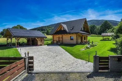 a log cabin with a pavilion next to a grassy field at Leśny Zakątek Jurków in Jurków