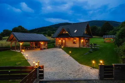 a log cabin with lights on the grass at Leśny Zakątek Jurków in Jurków