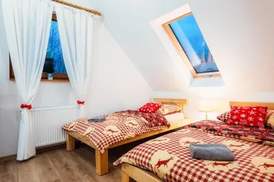 two beds in a room with two windows at Leśny Zakątek Jurków in Jurków