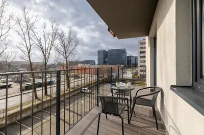 a balcony with a table and chairs and a view of a city at Modern Apartment with Parking in Cracow by Rent like home in Kraków