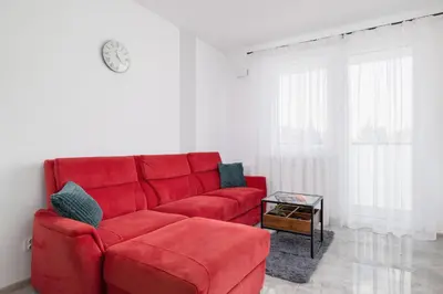 a red couch in a living room with a table at Kraków Elegant Apartment Near The Water Park by Rent like home in Kraków