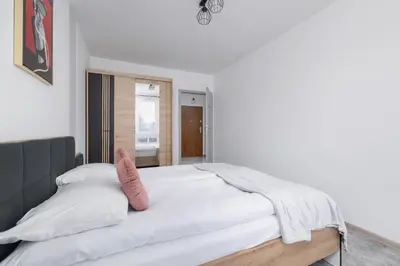 a bedroom with a white bed with a pink pillow at Kraków Elegant Apartment Near The Water Park by Rent like home in Kraków
