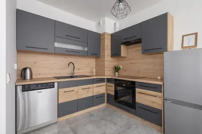 a kitchen with black and wooden cabinets and a refrigerator at Kraków Elegant Apartment Near The Water Park by Rent like home in Kraków