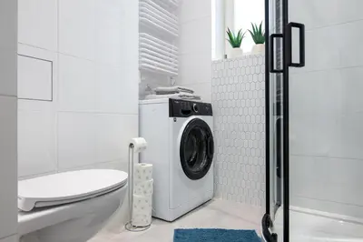 a white bathroom with a washing machine in it at Old Town Apartment Kazimierz in Kraków