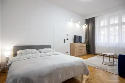 a white bedroom with a bed and a tv at Old Town Apartment Kazimierz in Kraków