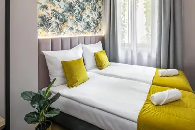 a white bed with yellow pillows and a window at Garden House Apartments in Kraków