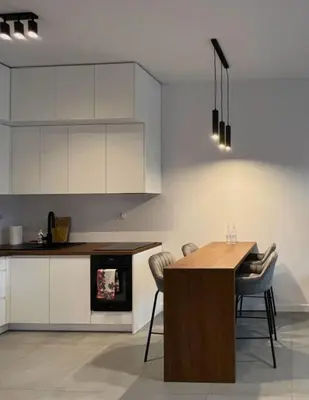 a kitchen with white cabinets and a table and chairs at Apartament Orawska in Kraków