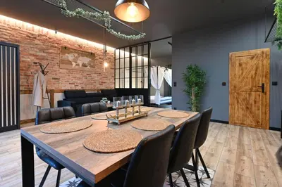 a dining room with a wooden table and chairs at Aparthotel Mamma Mia - Oświęcim in Oświęcim