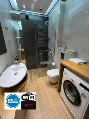 a bathroom with a washing machine and a washer at Bianco Apartament Reduta Park Free Parking in Kraków
