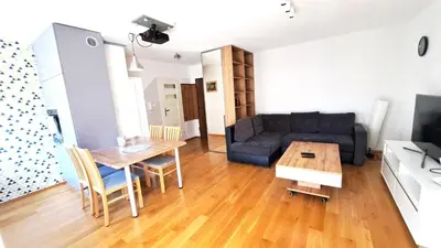 a living room with a couch and a table at Bianco Apartament Reduta Park Free Parking in Kraków