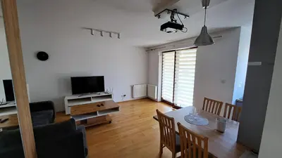 a living room with a dining table and a television at Bianco Apartament Reduta Park Free Parking in Kraków