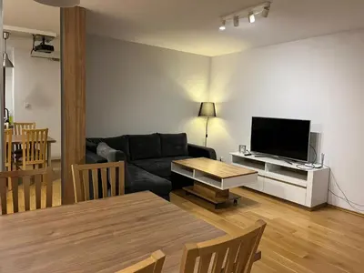 a living room with a couch and a tv at Bianco Apartament Reduta Park Free Parking in Kraków