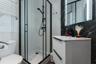 a kitchen with white cabinets and a stainless steel refrigerator at 70s Business Room in Kraków