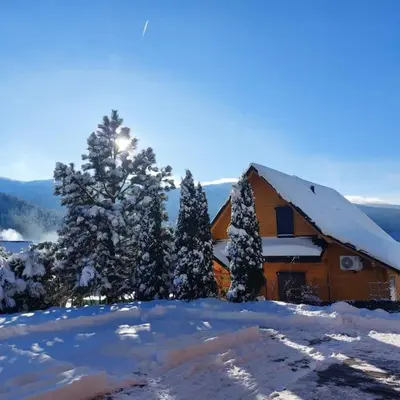 a house covered in snow with trees in the foreground at Panorama Sucha Góra in Skawica
