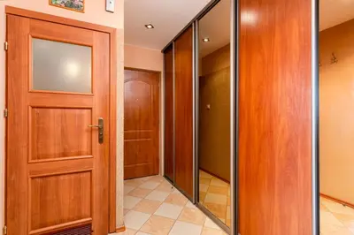 a hallway with a wooden door and a walk in closet at Zielona Nowa Huta Apartment by BookingHost in Kraków