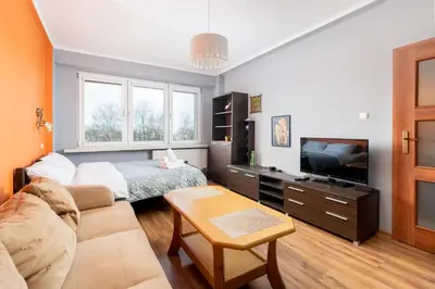 a living room with a couch and a tv at Zielona Nowa Huta Apartment by BookingHost in Kraków