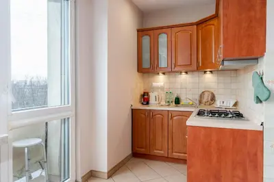 a small kitchen with wooden cabinets and a window at Zielona Nowa Huta Apartment by BookingHost in Kraków
