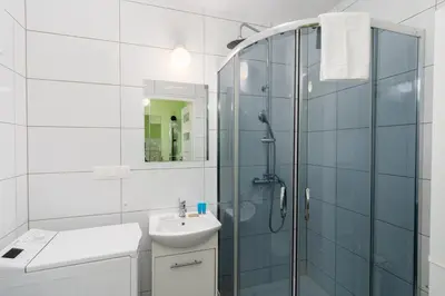 a white bathroom with a shower and a sink at Krowoderskich Zuchów Standard Studio by BookingHost in Kraków