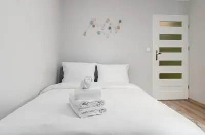 a white bed with white sheets and towels on it at Krowoderskich Zuchów Standard Studio by BookingHost in Kraków