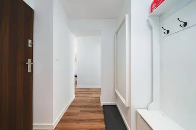 a hallway with white walls and a wooden door at Close to everywhere, cosy place in Kraków